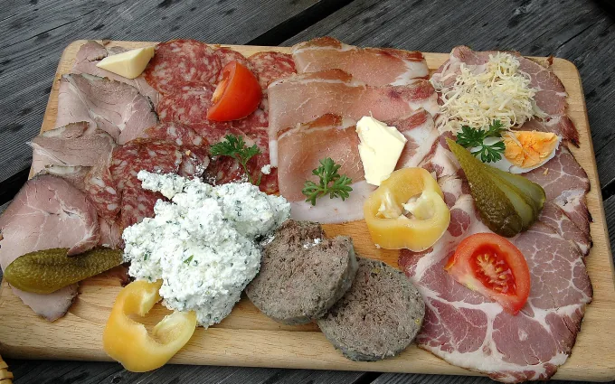 Brettljause mit Selchfleisch, Salami, Speck, Topfenaufstrich, Gurkerl und Ei auf einem Holzbrett